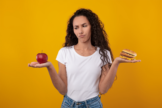 A woman deciding between an apple and a less healthy sandwich